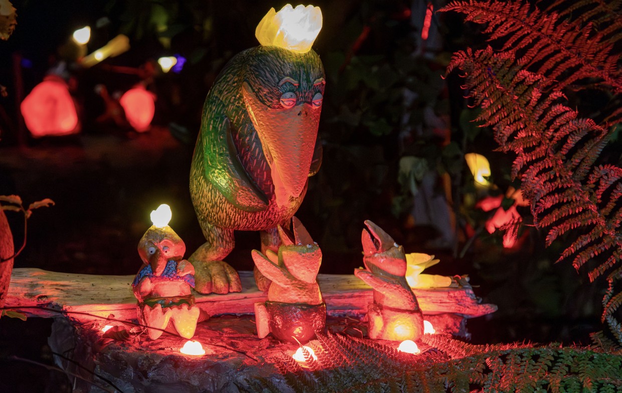 Small and large glowing bird sculptures nestled in native ferns