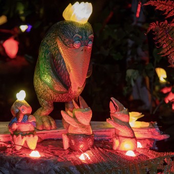 Small and large glowing bird sculptures nestled in native ferns